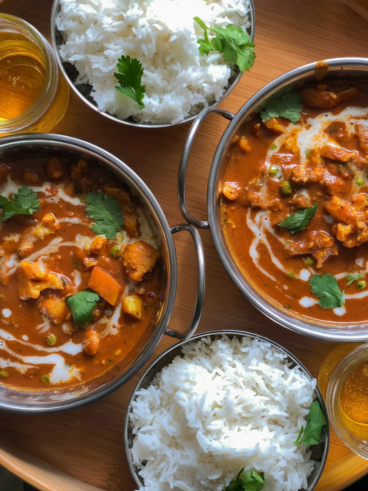 Bowls of curry with rice, naan and chutneys on a table