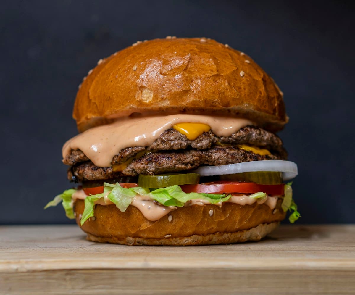 Double cheeseburger with lettuce and tomato on a wooden board