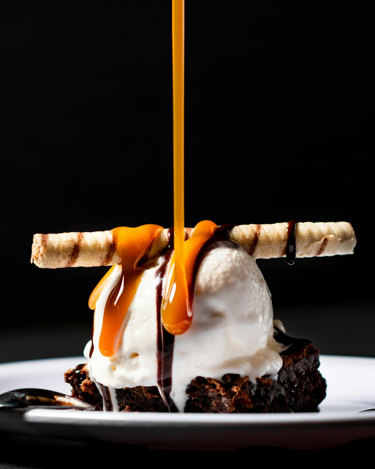 Ice cream sundae with caramel sauce being poured over the top